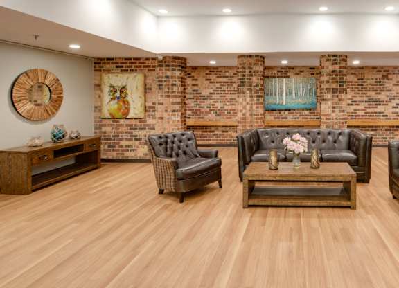 A living room with a brick wall and wooden floors.