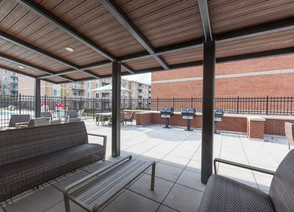 A patio with a couch and chairs under a wooden roof.