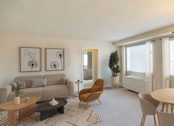 A living room with a grey couch, a wooden coffee table, a round table, and a chair.