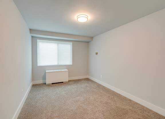 A room with a window and a white box on the floor.