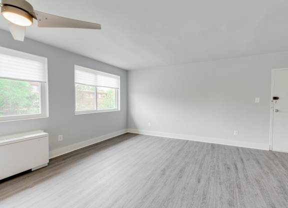 A room with a ceiling fan and a window with blinds.