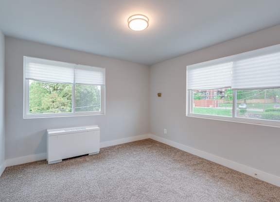 A room with a window and a carpeted floor.