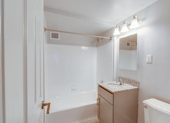 A white bathroom with a tub, sink, and mirror.