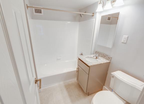 A white bathroom with a toilet, sink, and bathtub.