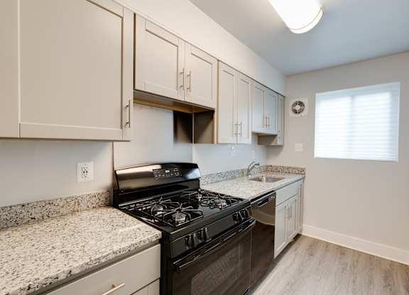 A kitchen with a black stove top oven and a granite counter top.