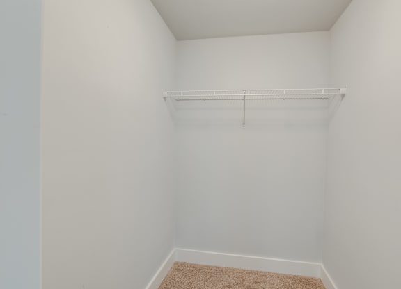A small, empty room with a shelf and carpeted floor.