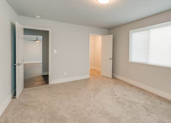 A room with a carpeted floor and a window with blinds.