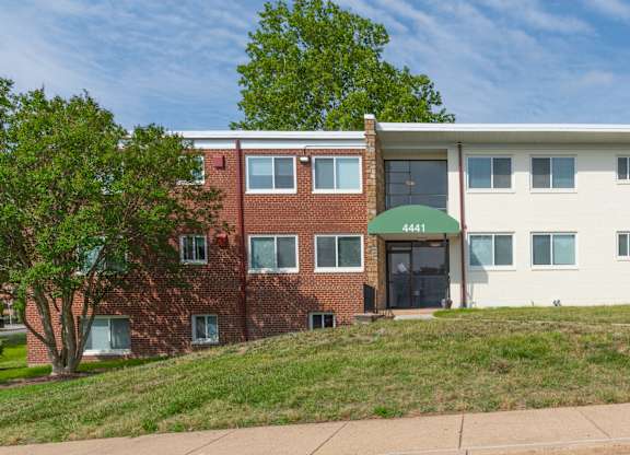 A building with a green awning sits on a grassy hill.