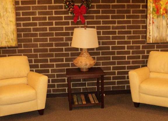 Two chairs and a table with a lamp on it.