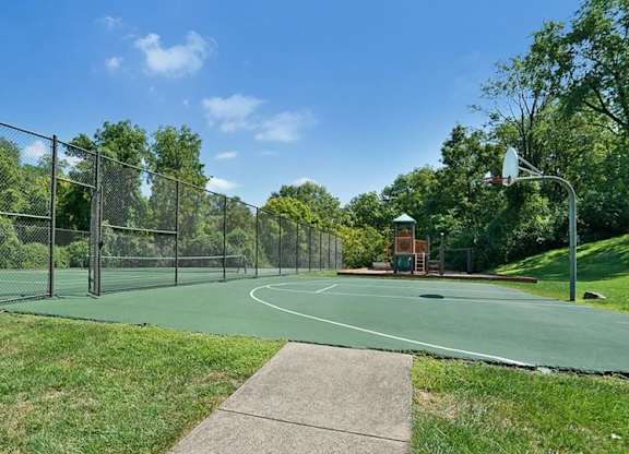 A basketball court surrounded by a fence and trees.
