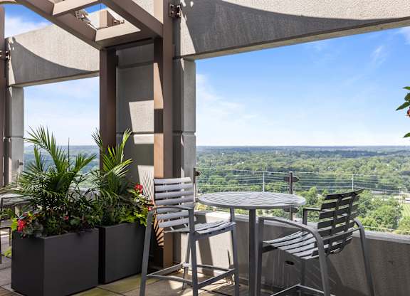 A patio with a table and chairs overlooking a valley at Clayton on the Park Apartments, Clayton 63105