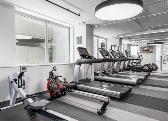 A gym with treadmills, elliptical machines, and a rowing machine at Clayton on the Park Apartments, Clayton 63105