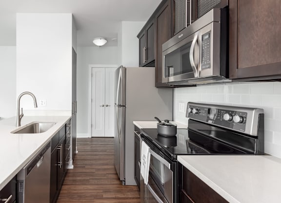 A modern kitchen with dark wood cabinets and stainless steel appliances at Clayton on the Park Apartments, Clayton, MO