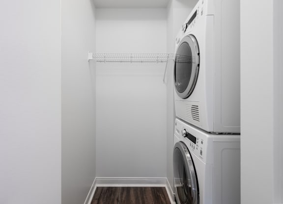 A white laundry room with a washer and dryer stacked on top of each other at Clayton on the Park Apartments, Clayton 63105