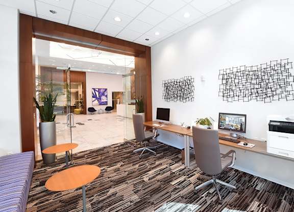 A modern office with a purple sofa and a wooden desk.