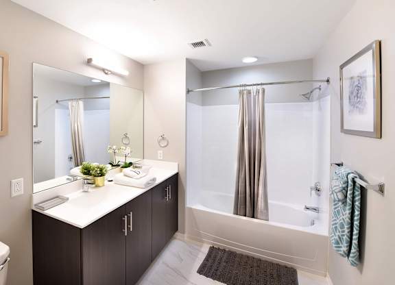 A bathroom with a white counter top and a shower with a glass door.