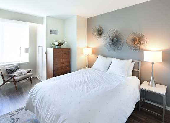 A bedroom with a large bed and a chair by the window.