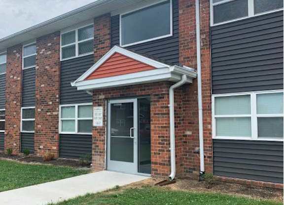 a brick apartment building with a front door and grass
