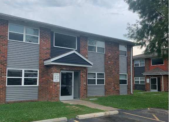 the front of a building with a parking lot and grass