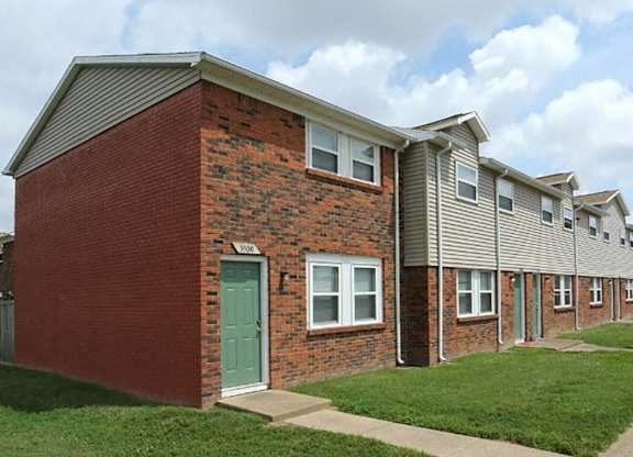 the front of a brick apartment building with a green door