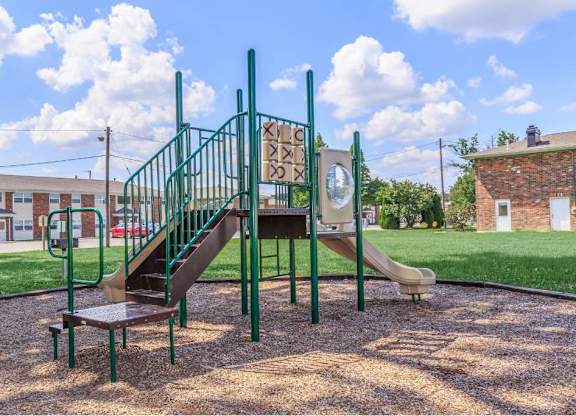 a playground with a slide and stairs in front of a building