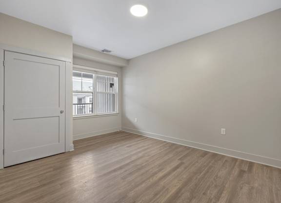 A room with a white door and wooden flooring.