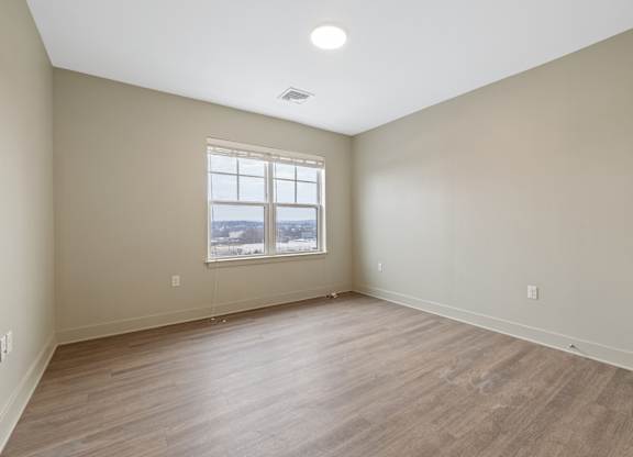 Empty room with a window and wooden flooring.