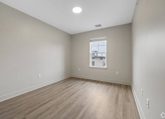 A room with a window and wooden flooring.