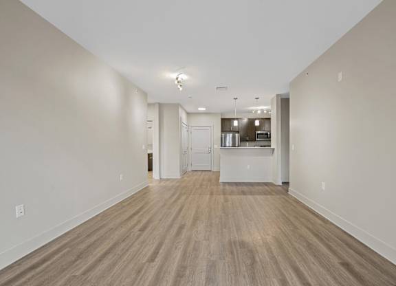 A long, empty hallway with wood flooring and white walls.