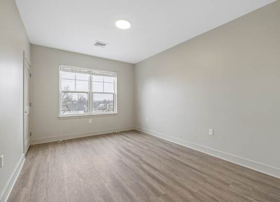 A room with a window and wooden flooring.