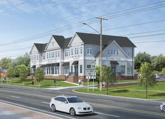 A white car is driving on a street past a house.