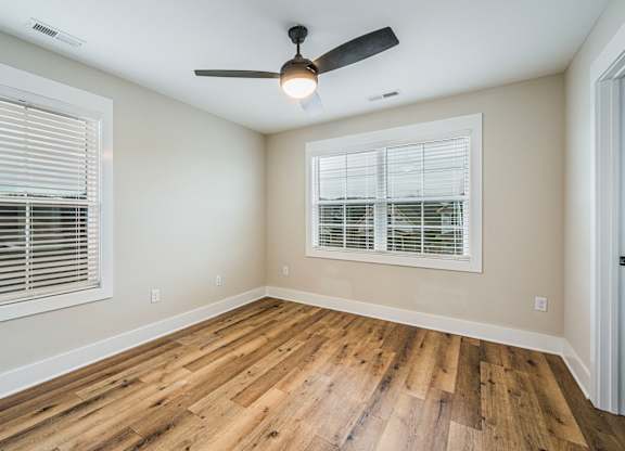 A room with a ceiling fan and wooden flooring.