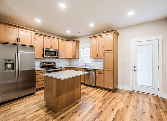 A kitchen with wooden cabinets and a wooden island.