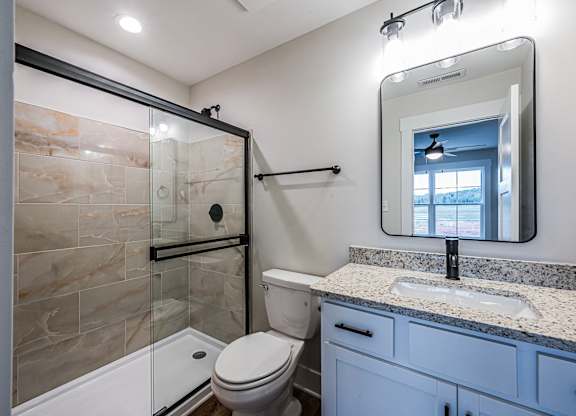 A bathroom with a toilet, sink, and mirror.