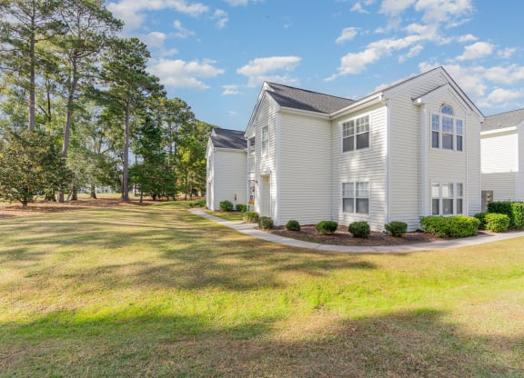 a white house with a yard and trees in front of it