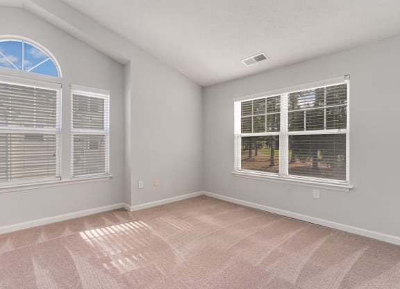 an empty living room with windows and carpeting