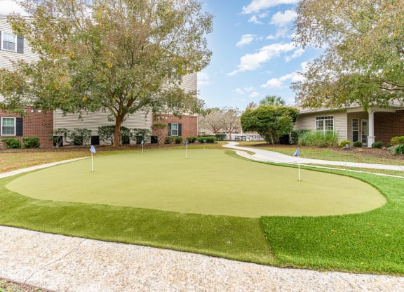 a putting green in front of a house with trees and condos at Litchfield Oaks Apartments, Pawleys Island