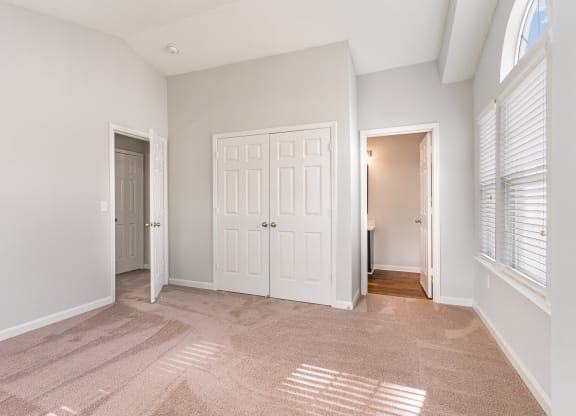 an empty living room with two doors and a door to a hallway