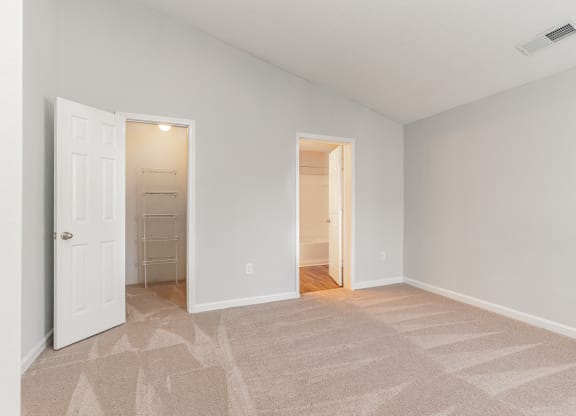 an empty bedroom with a closet and a door to a bathroom