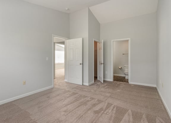 a spacious living room with carpet and a door to a bathroom