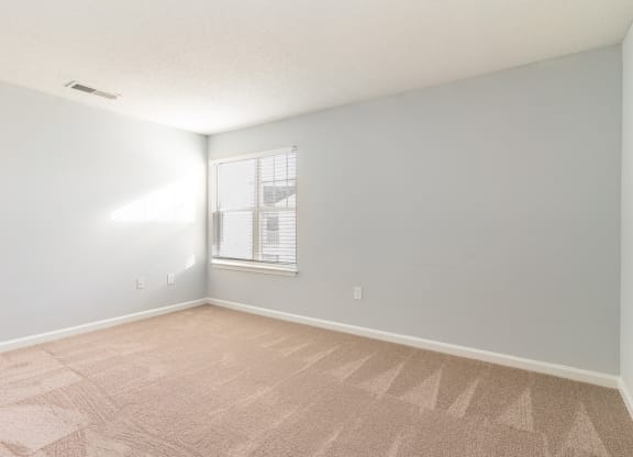 an empty room with a window and a carpeted floor