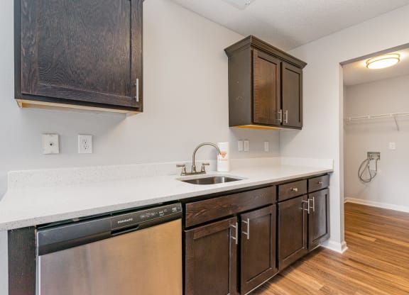 a kitchen with dark cabinets and a sink and a dishwasher