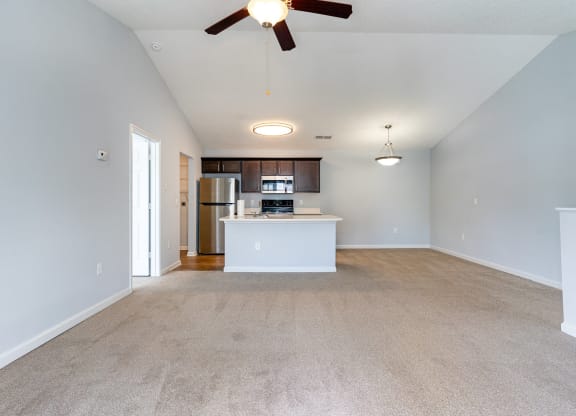 an empty living room and kitchen with a ceiling fan
