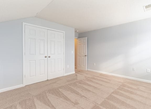 an empty living room with white doors and a carpeted floor