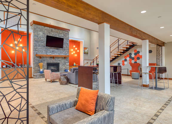 A modern living room with a grey couch and a stone fireplace.