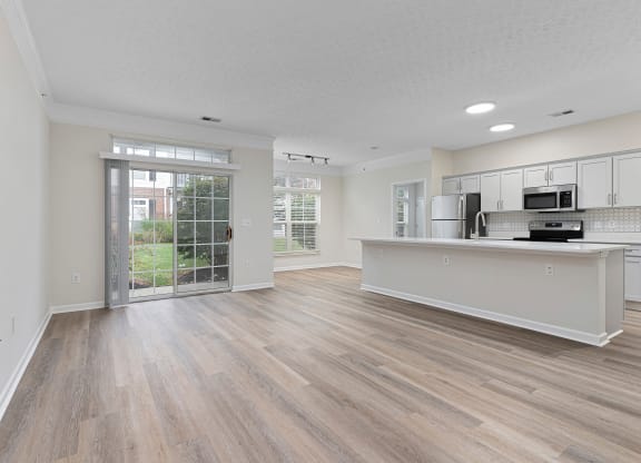 an open living room and kitchen with a door to a patio  at The Charleston, Columbus