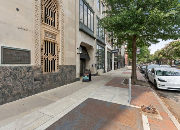 a sidewalk with a tree and cars parked on the side of the road