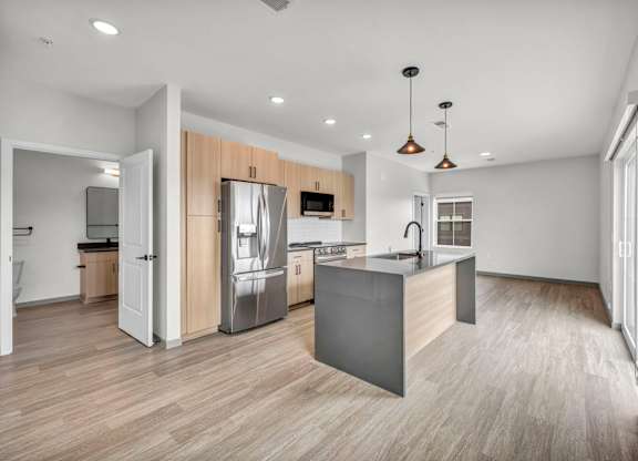 A modern kitchen with a refrigerator, microwave, and oven.