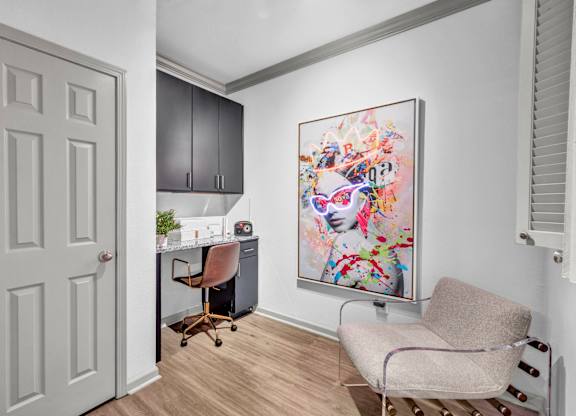 A room with a chair, a desk, and a painting on the wall.