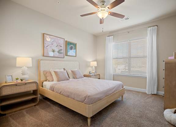 A bedroom with a bed, nightstand, and a ceiling fan.